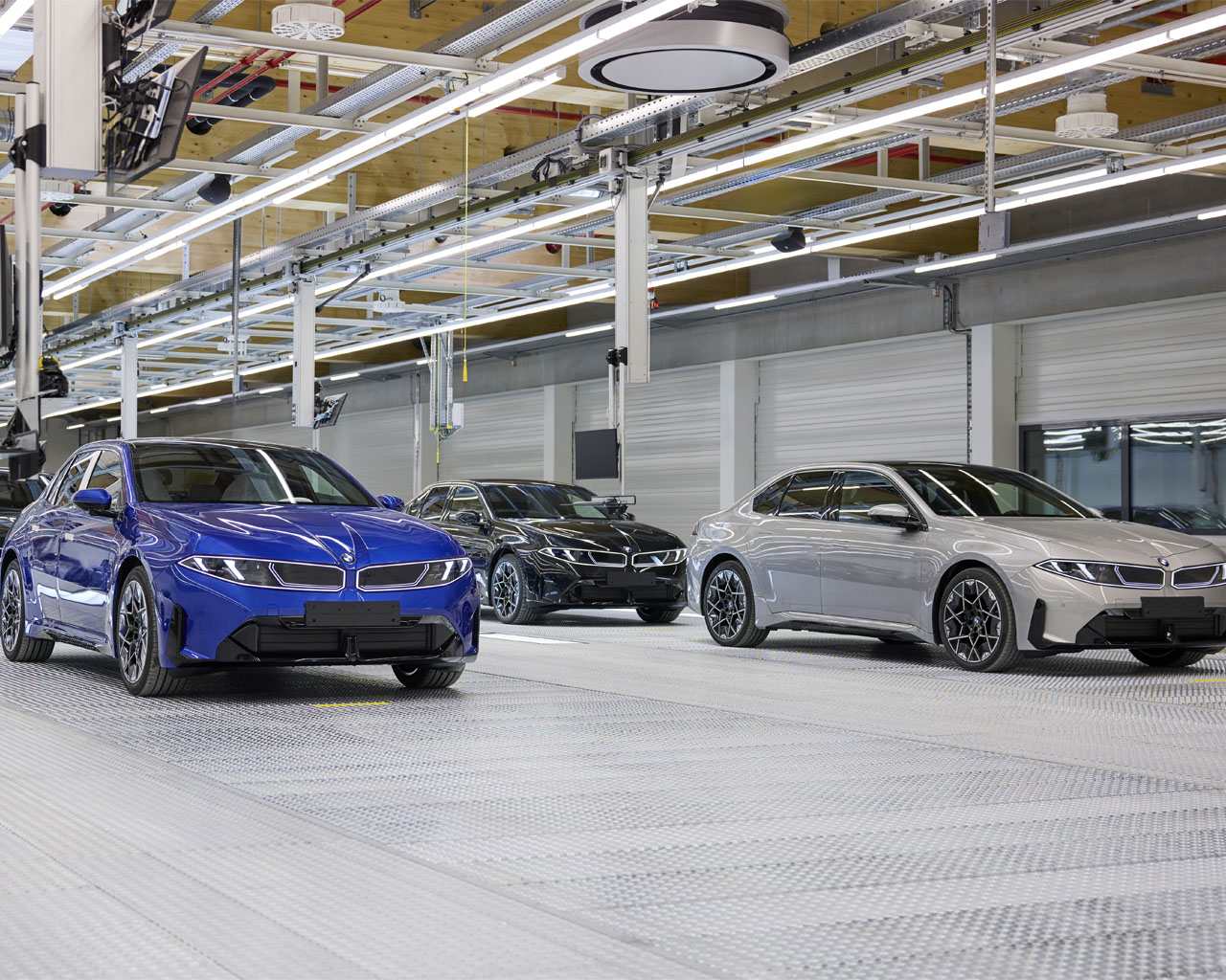 Several new BMW i3 vehicles in blue, silver and black are lined up in the assembly hall of BMW Group Plant Munich.