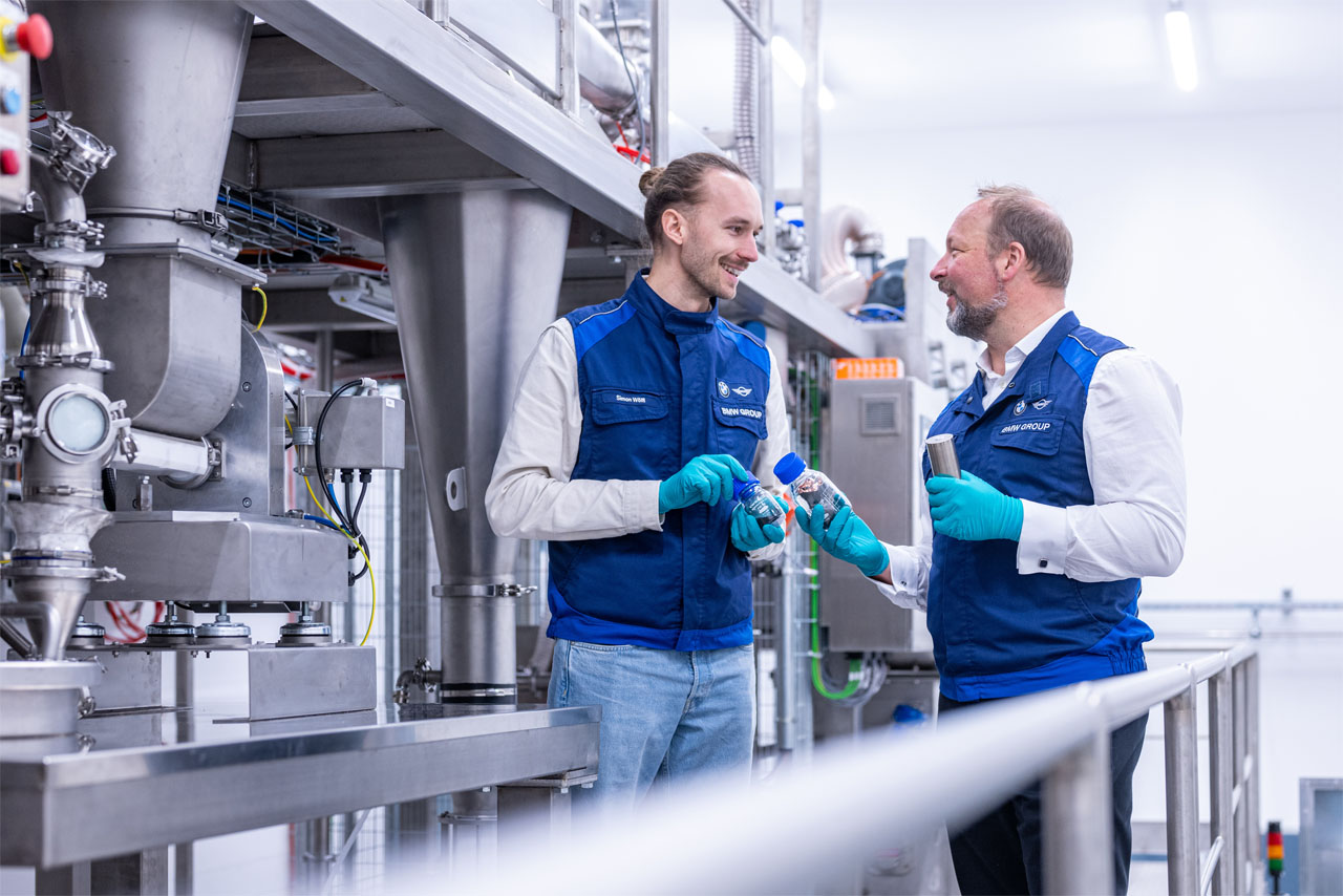 Zwei Experten begutachten Proben recycelter Batterierohstoffe an einer Anlage für Elektrodenrecycling im BMW Group Kompetenzzentrum Batteriezellrecycling (CRCC) in Salching.