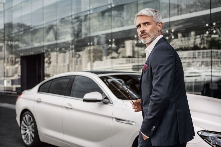 A man in a suit walks by his BMW 6 Series Gran Coupé.