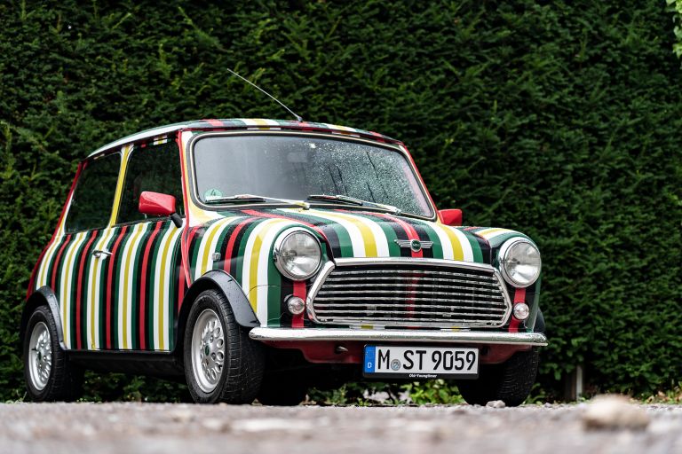 A striped MINI in front of a hedge