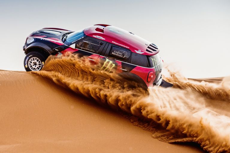 A MINI John Cooper Works driving up a dune in the desert.