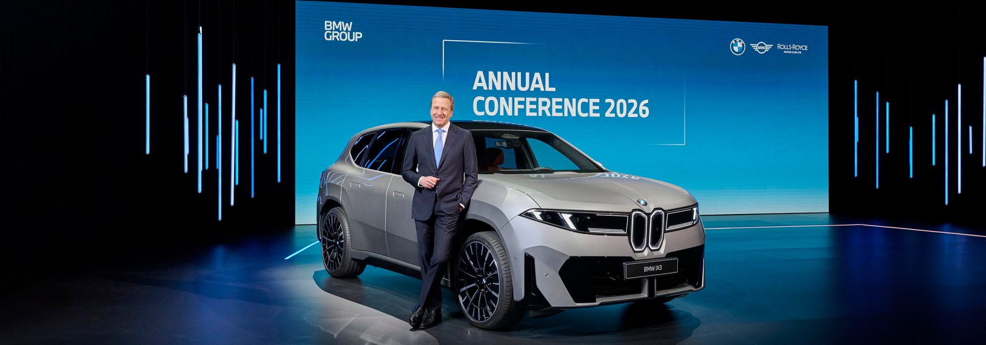 Bühnenauftritt: Oliver Zipse, Vorstandsvorsitzender der BMW AG, lehnt an der Seite eines vollelektrischen BMW iX3 auf der BMW Group Jahreskonferenz 2026 in München.