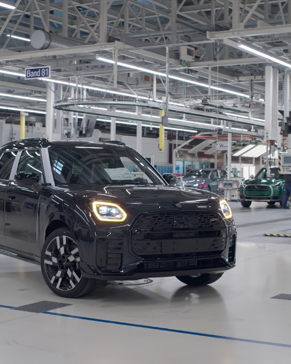 Schwarzes, fahrerloses Fahrzeug der Marke Mini fährt durch eine Werkshalle.
