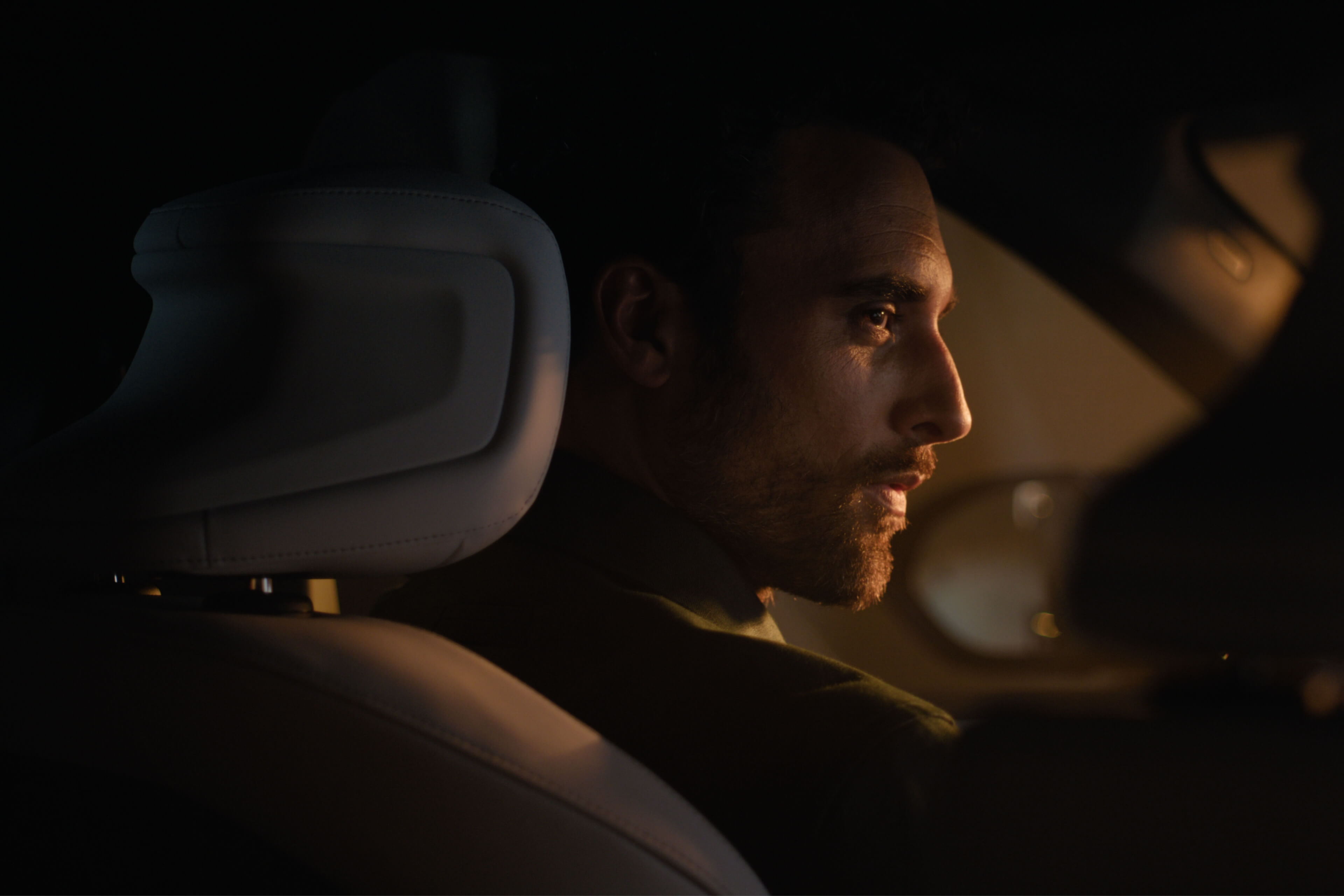 Person im Fahrzeug blickt zur Seite, warm vom Innenlicht beleuchtet.