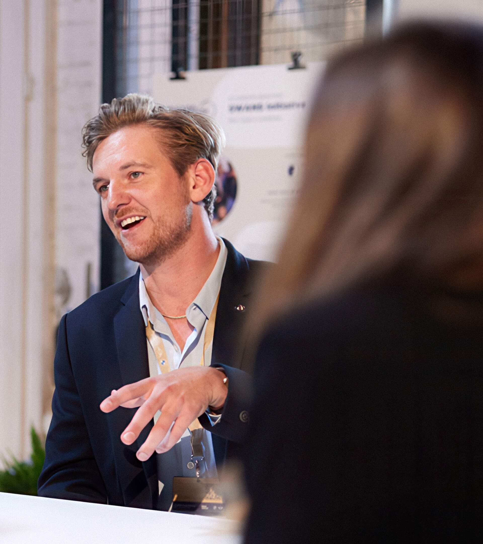 Eine Person mit Namensschild spricht mit einer anderen Person, beide halten Whiteboard-Stifte in der Hand.