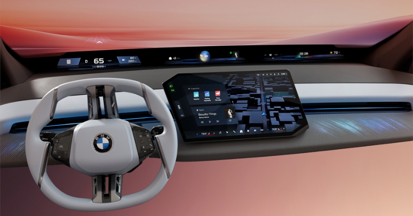 Digitales BMW Cockpit mit futuristischem Lenkrad, breitem Informationsdisplay und zentralem Touchscreen mit Navigations- und Medienfunktionen.