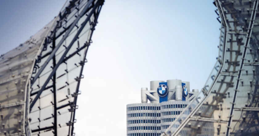 Die BMW Firmenzentrale erscheint zwischen zwei gebogenen Glas‑ und Stahlstrukturen der 