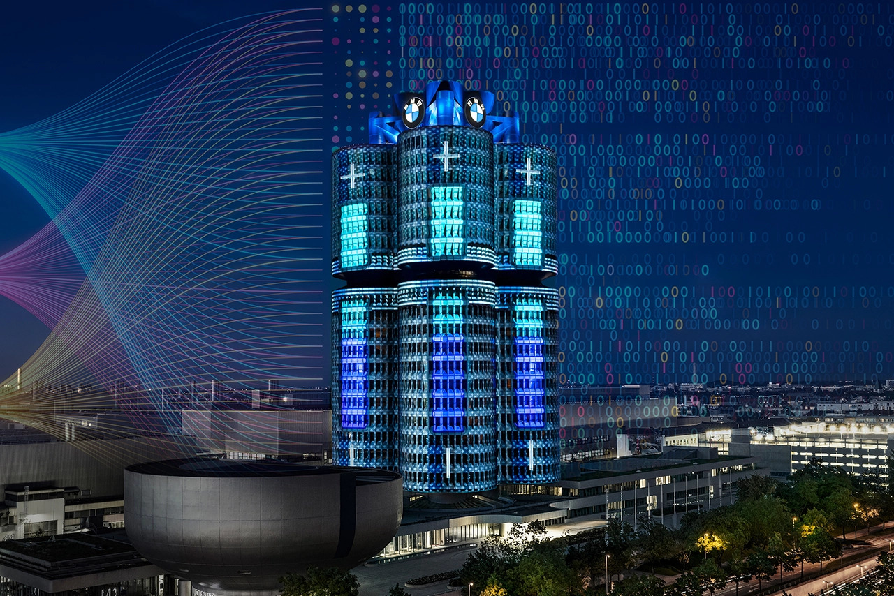 Das BMW Gebäude in München beleuchtet mit farbigen Lichtern und digitalen Mustern.