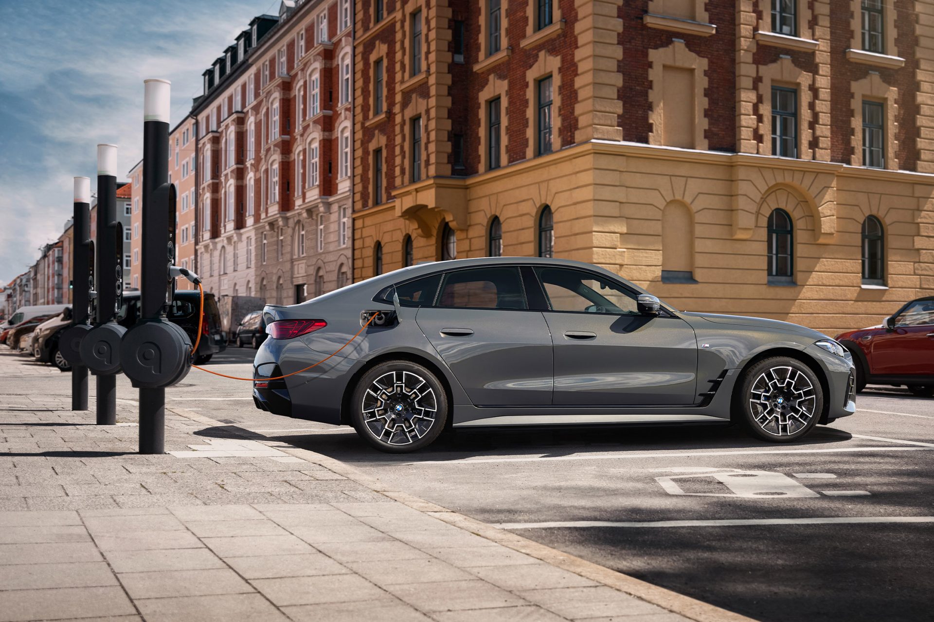 Grauer BMW i4 an einer Ladesäule in einer Innenstadt.