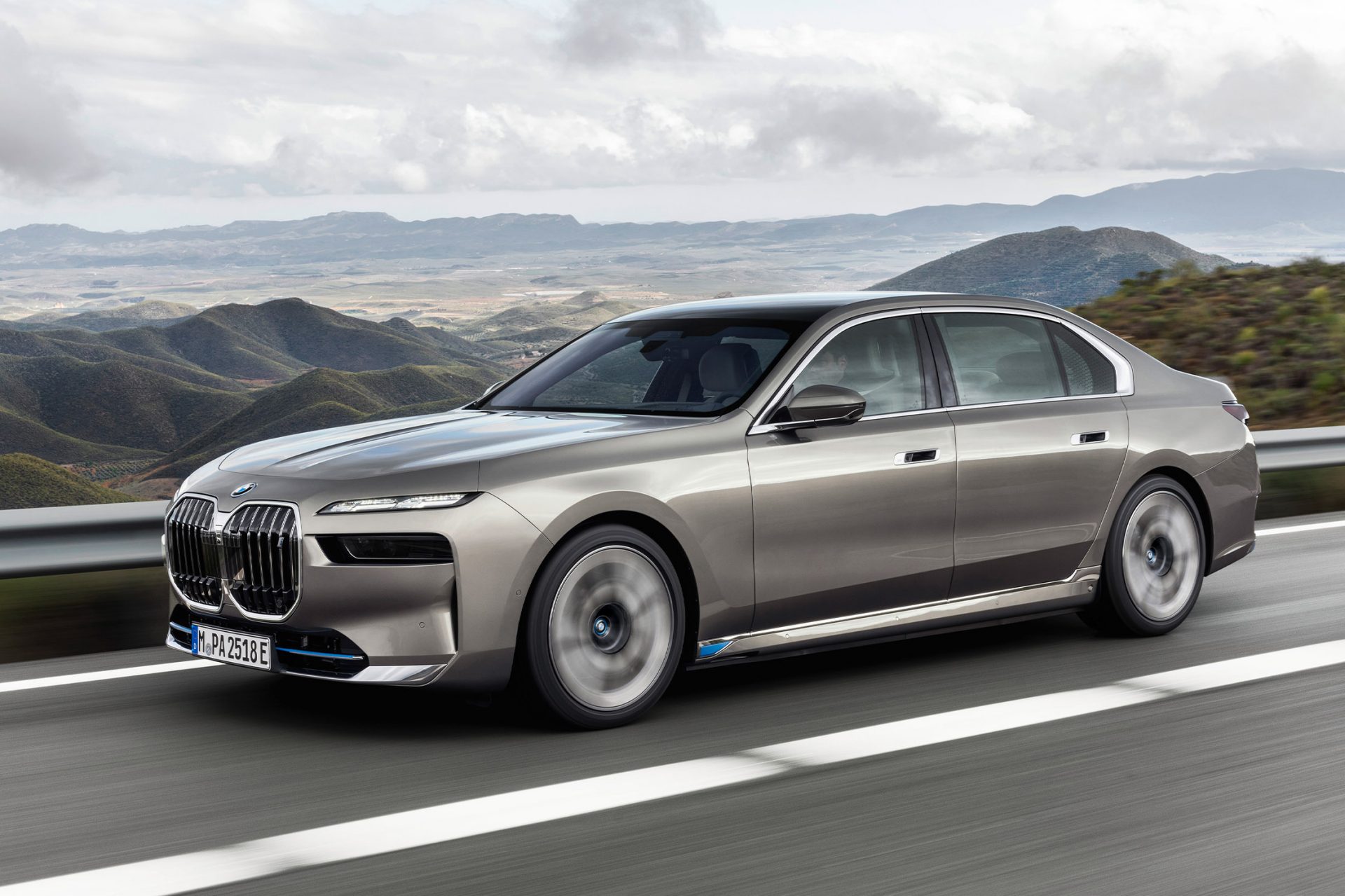 Grauer BMW i7 fährt auf einer Landstraße mit einem Tal im Hintergrund.