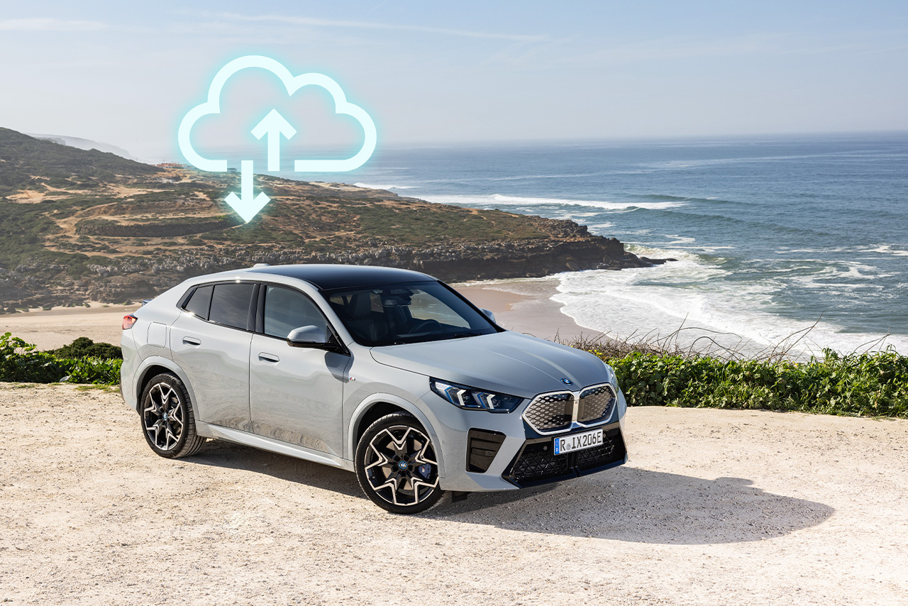 BMW Fahrzeug steht auf einem Vorsprung neben dem Meer, darüber ein Upload und Download Icon