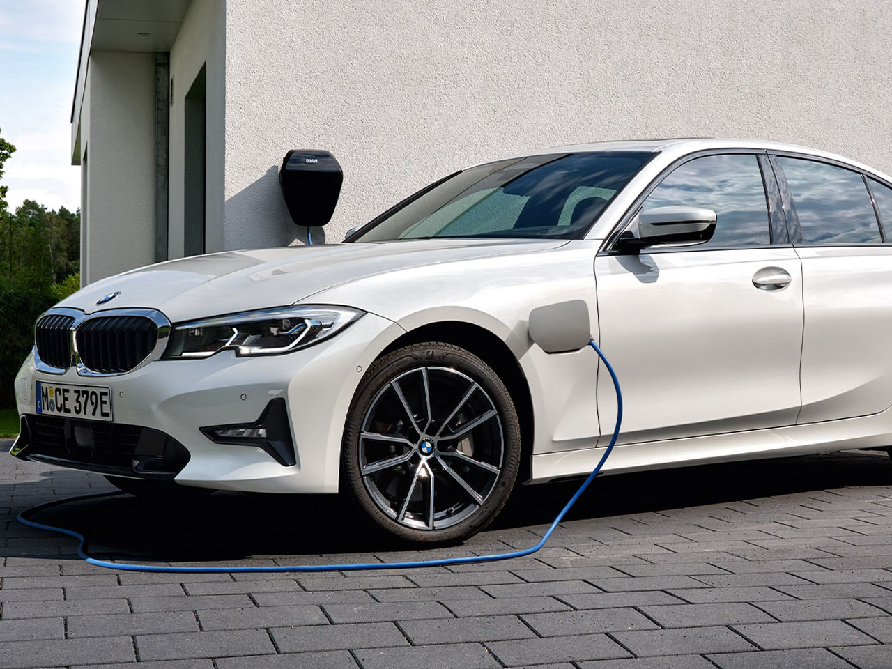Weißer 3er BMW steht zum Laden vor dem Haus.