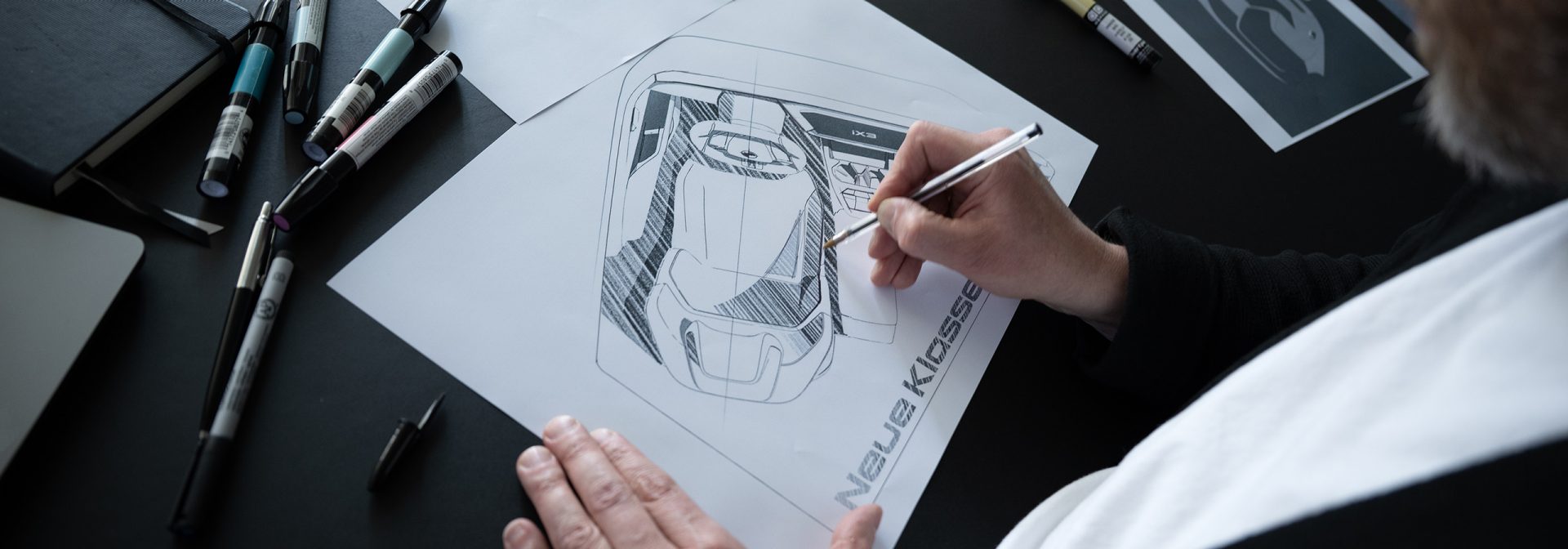 Eine Hand skizziert ein BMW Fahrzeug.