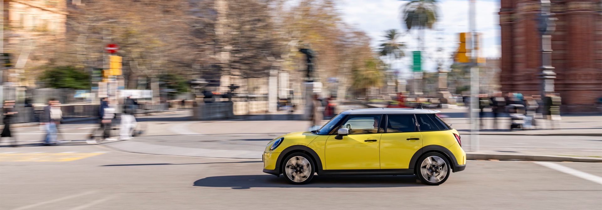 Ein gelber Mini Cooper bewegt sich durch eine belebte Stadtstraße.