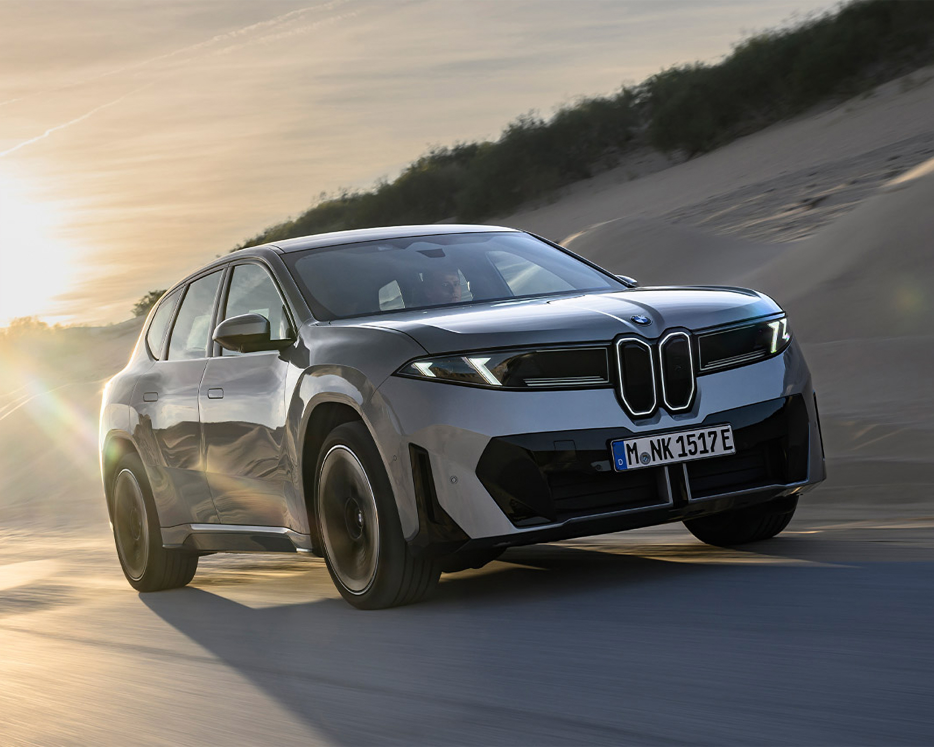 Silber BMW iX3 fährt durch eine Wüste.