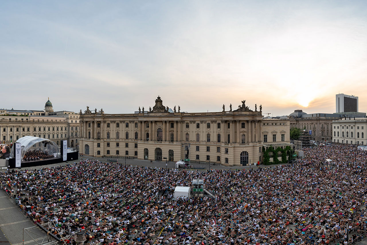 Ein Konzert in einer Stadt zwischen historischen Gebäuden, davor eine Menschenmenge