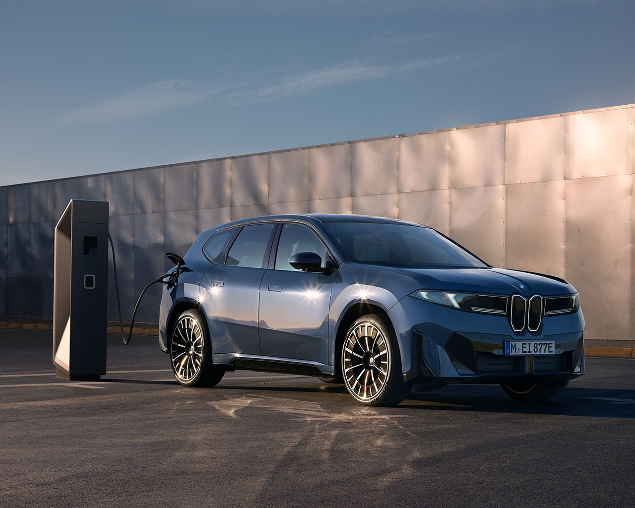 Eine BMW Neue Klasse ist auf einem Ladegerät ausgestellt, das auf einer Plattform in einer natürlichen Umgebung steht.
