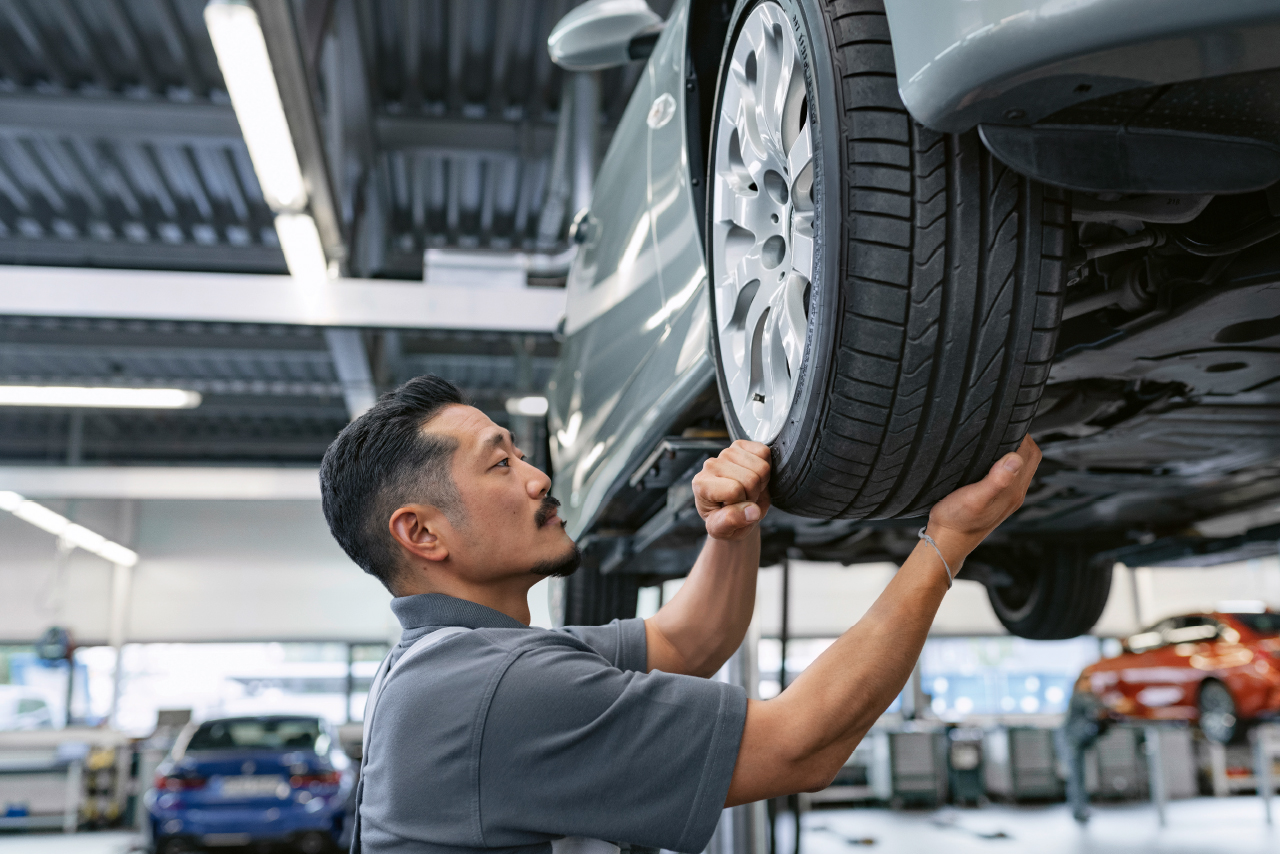  Ein Mann arbeitet an einem Auto in einer Garage, um Reparaturen durchzuführen.