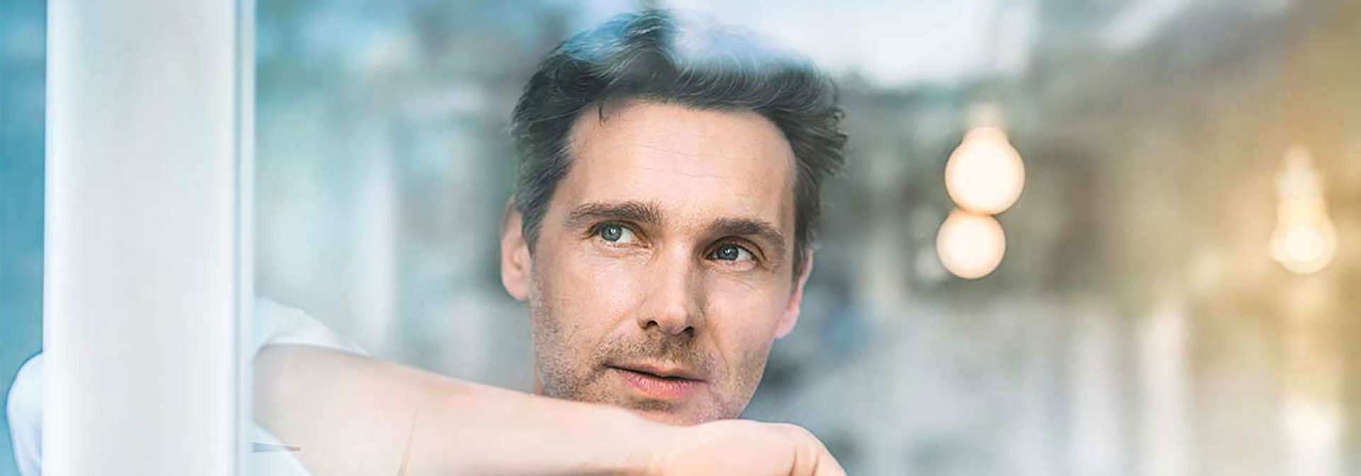 Junger Mann schaut aus dem Fenster