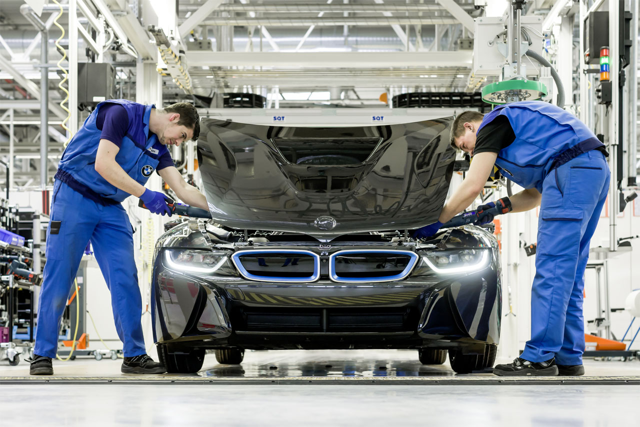 Montage eines BMW i8 mit geöffneter Haube im BMW Group Werk Leipzig: Zwei Werker arbeiten parallel an der Frontpartie.