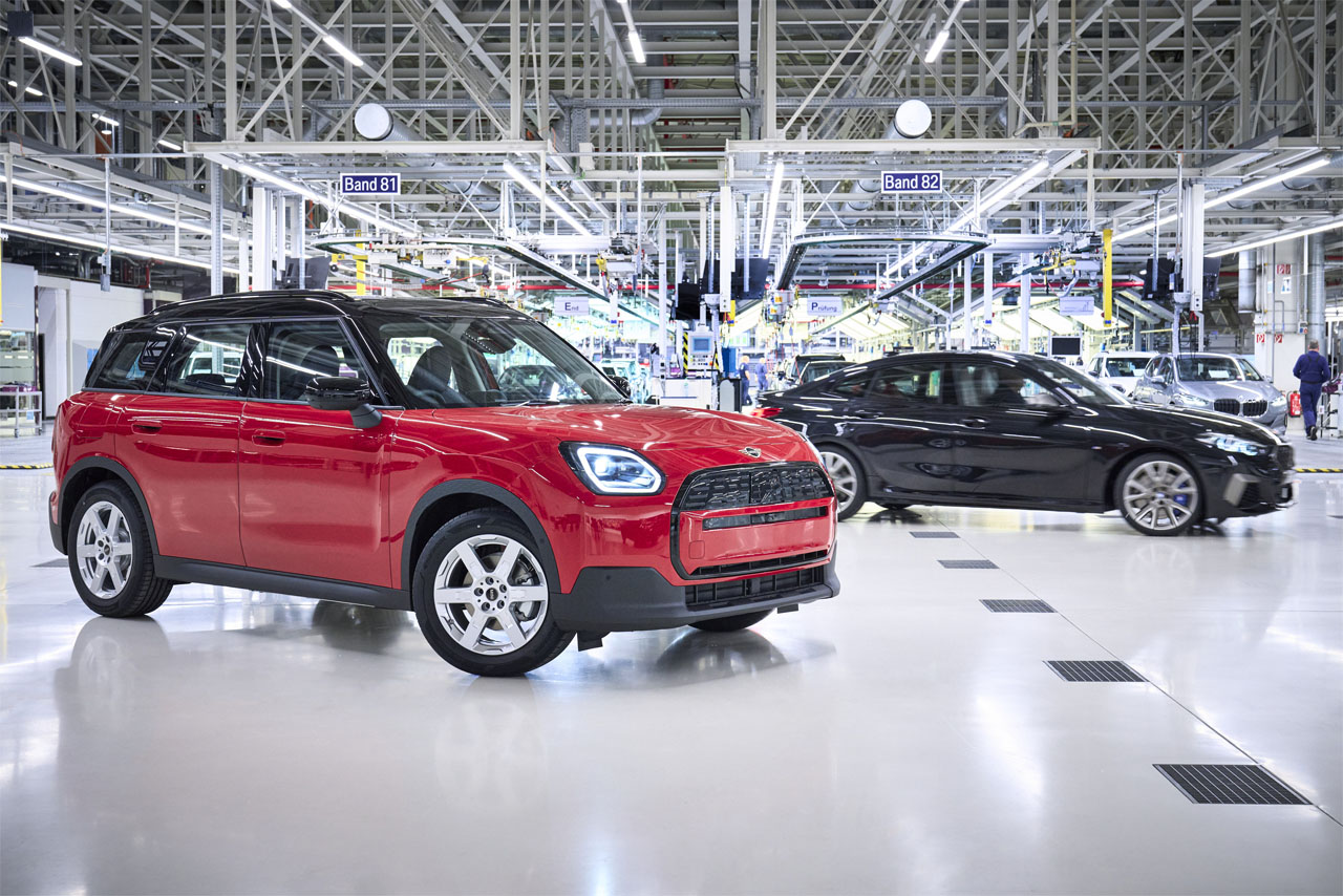 Produktionsszene: Schrägansicht auf Front und Beifahrerseite eines roten MINI Countryman E mit schwarzem Dach im BMW Group Werk Leipzig.