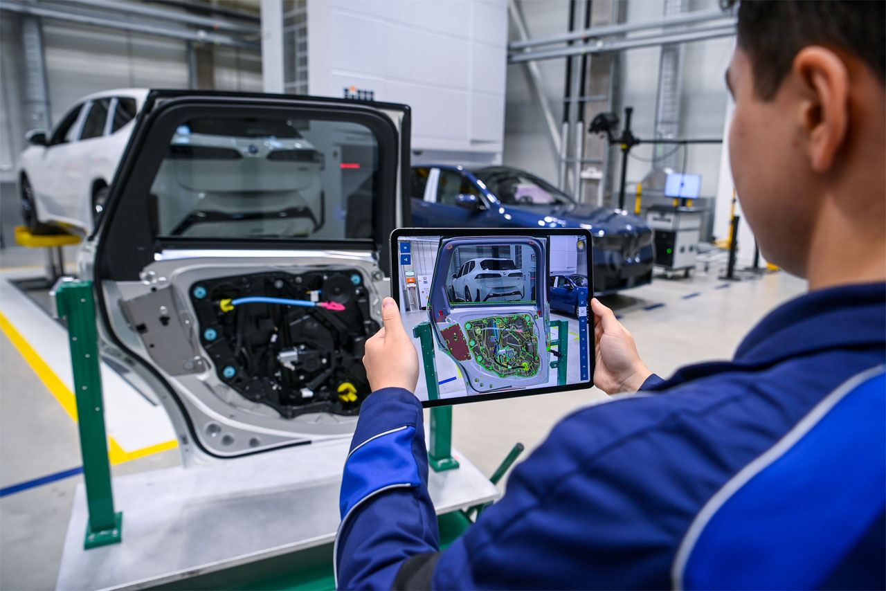 Zur Qualitätskontrolle inspiziert ein Werker per Tablet die unverkleidete Türinnenseite eines BMW iX3 im BMW Group Werk in Debrecen.