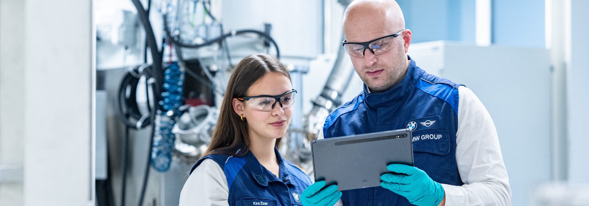 Zwei Mitarbeitende der BMW Group analysieren KI-gestützte Daten aus der Batteriezellfertigung auf einem Tablet.