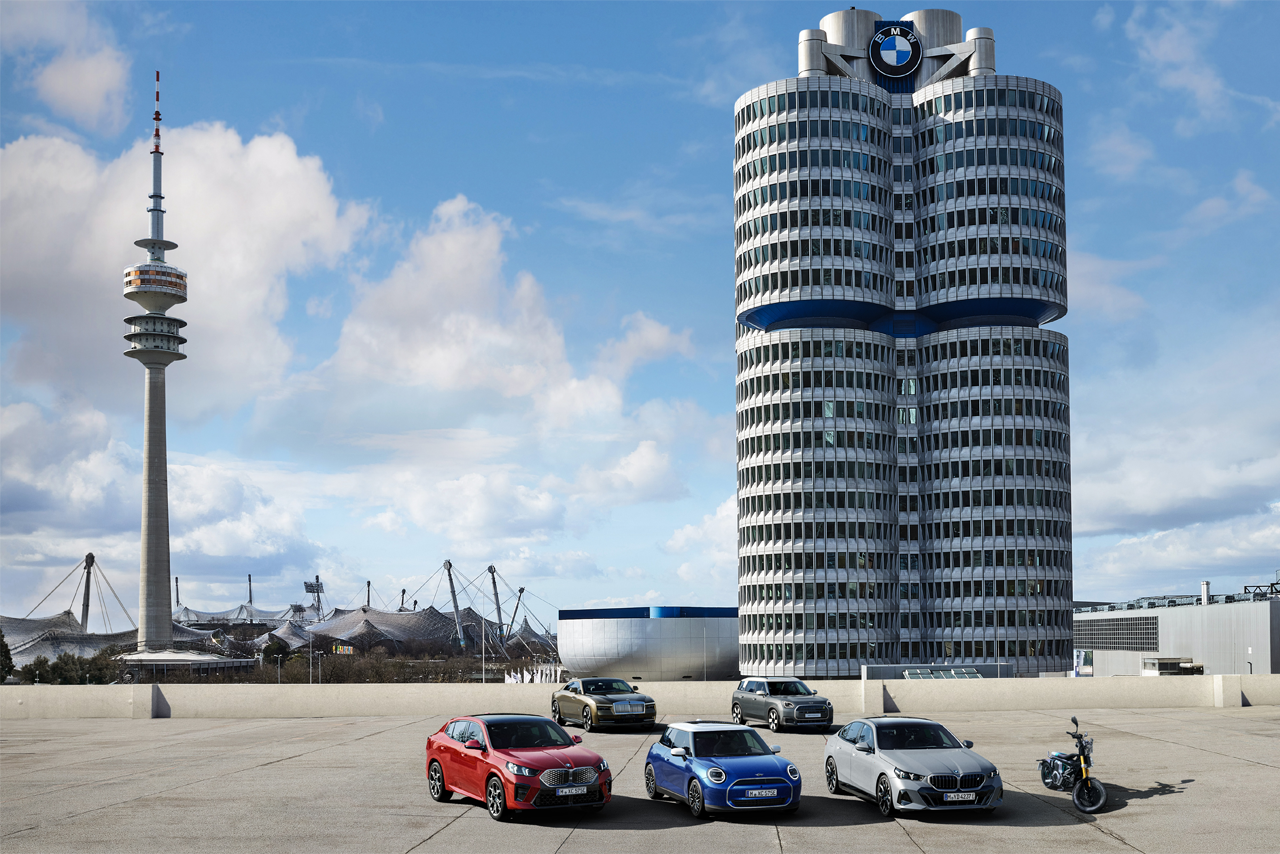 Blick auf das BMW Vierzylinder-Gebäude mit davor parkenden Fahrzeugen.