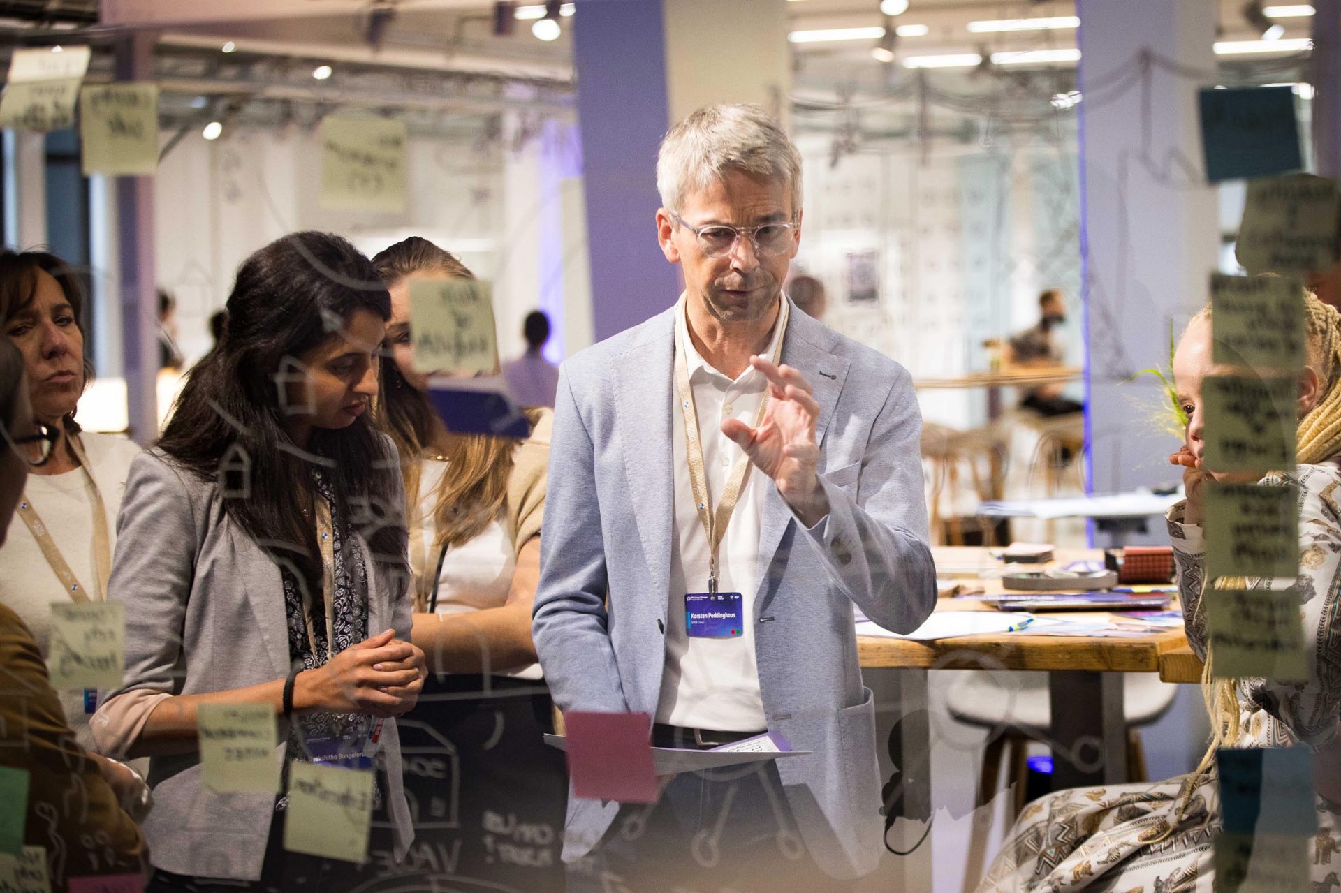  Teilnehmer einer Teamdiskussion mit Haftnotizen im Hintergrund