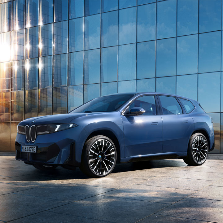 Design‑Artwork: Seitenansicht des vollelektrischen BMW iX3, inszeniert vor moderner Glasfassade im Sonnenlicht.