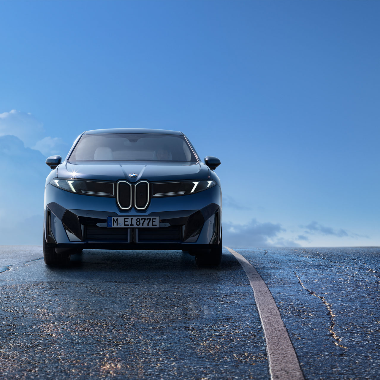 Vorderansicht eines BMW iX3 auf einer Straße unter blauem Himmel.