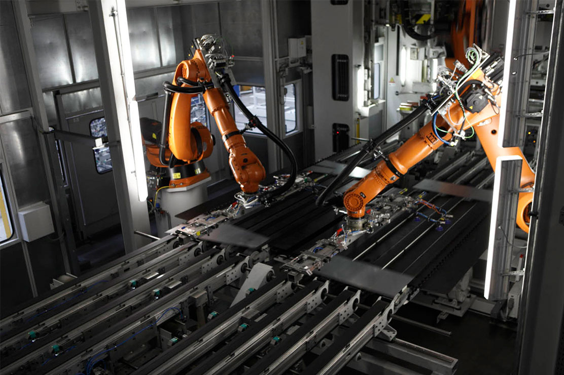 Roboterarme legen Blechteile auf einem Förderband ab