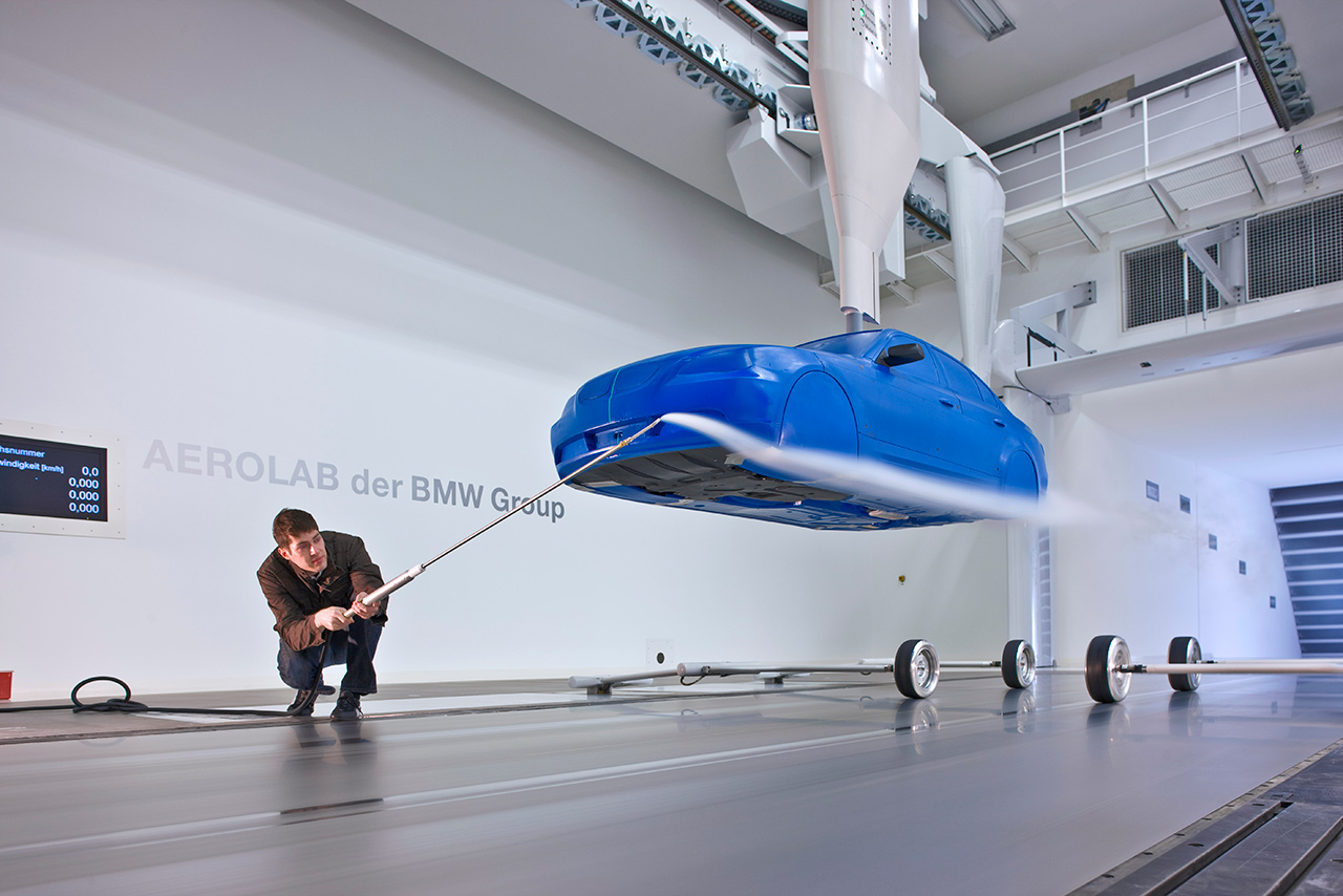 Ein Mitarbeiter justiert im Modellwindkanal des Aerodynamischen Versuchszentrums ein Fahrzeugmodell mit einer Stange.