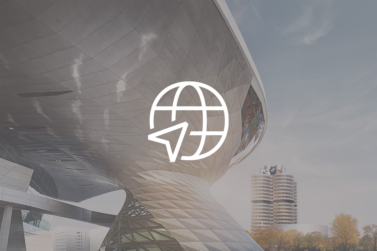 Weltkugel Icon mit Pfeil darauf, im Hintergrund die BMW Welt und das BMW Hauptquartiert.