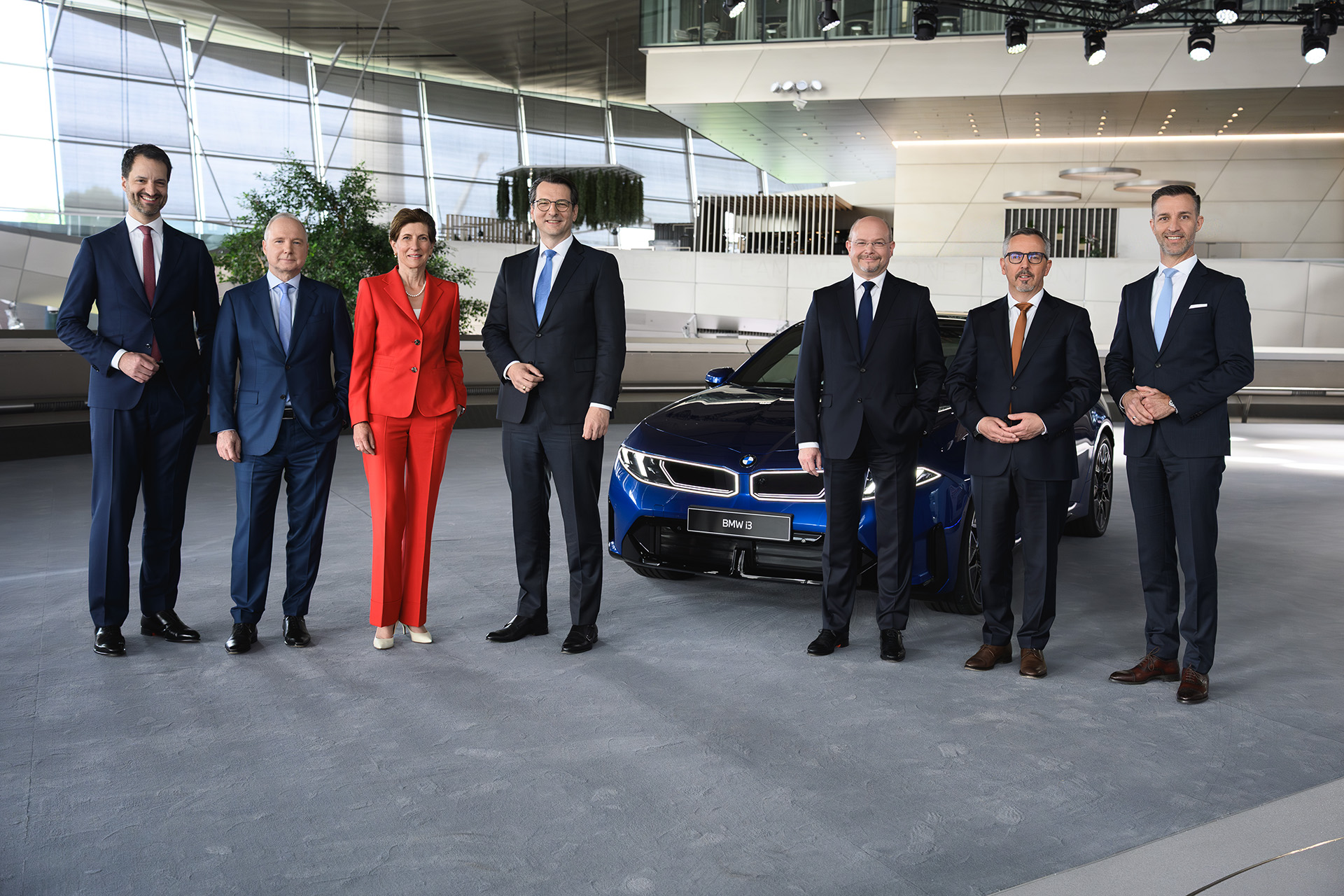 The BMW Group board members are standing next to a blue BMW iX3