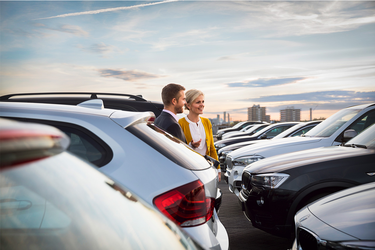 A Alphabe employee is touring the parking lot with lots of BMW vehicles together with a customer.