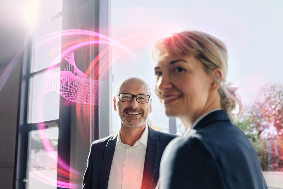 A man and a woman stand next to each other. Around them are pink light shapes