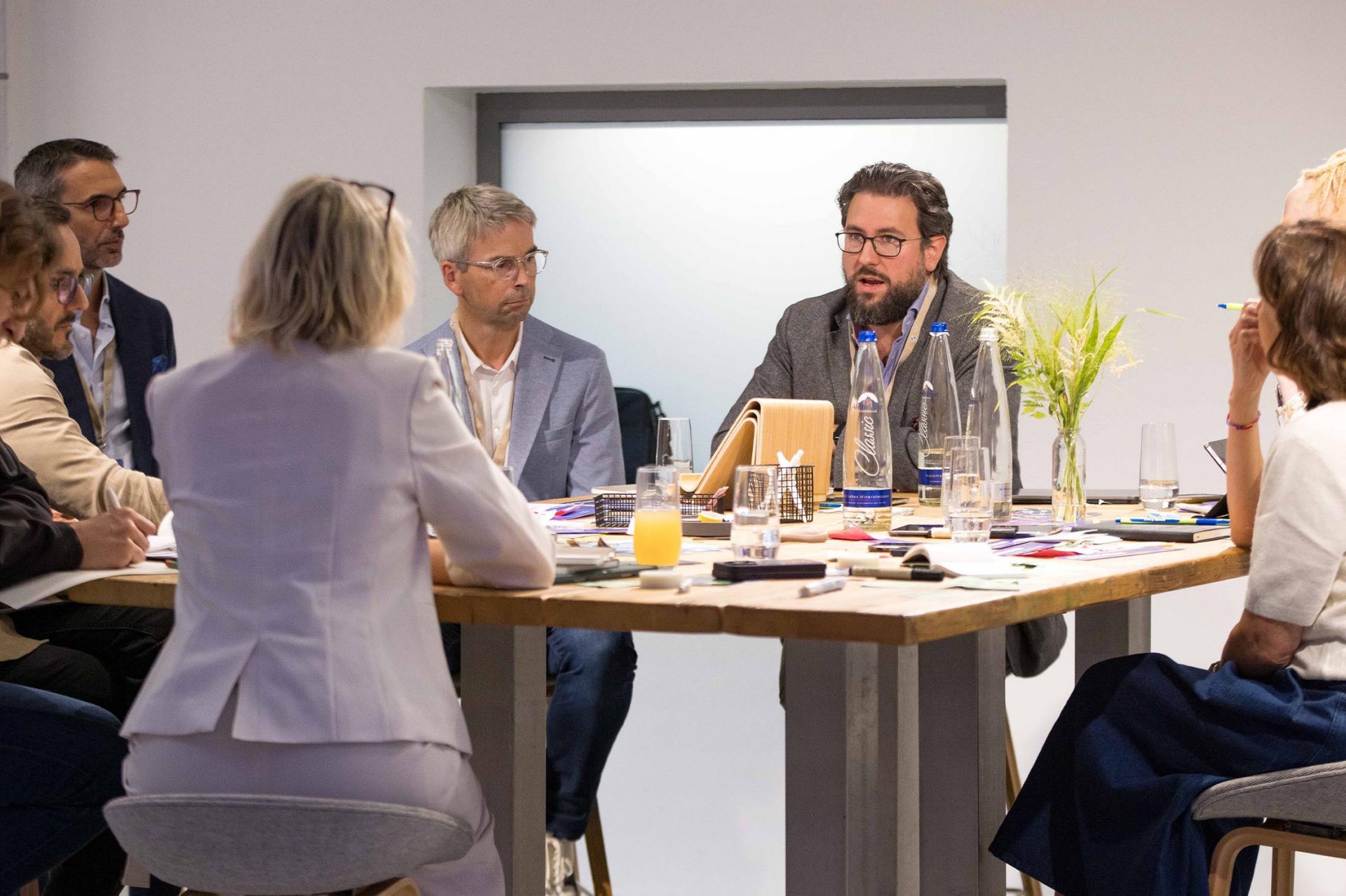   A team in a meeting around a table with notes and drinks.