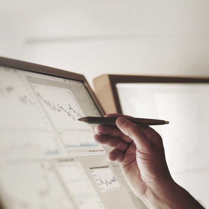 A hand draws with a pen on a monitor.