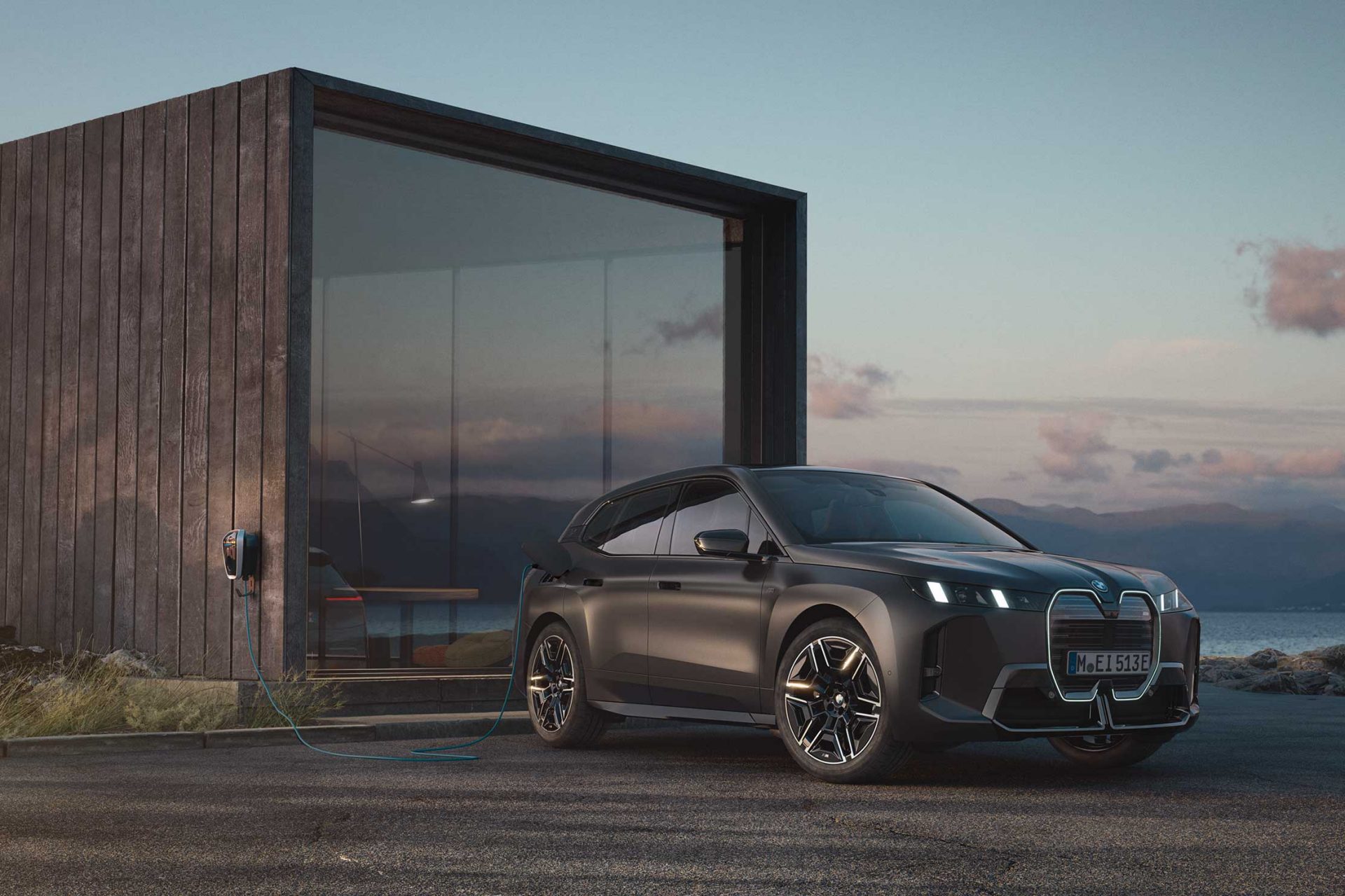 BMW iX M70 infront of a modern wooden hut.