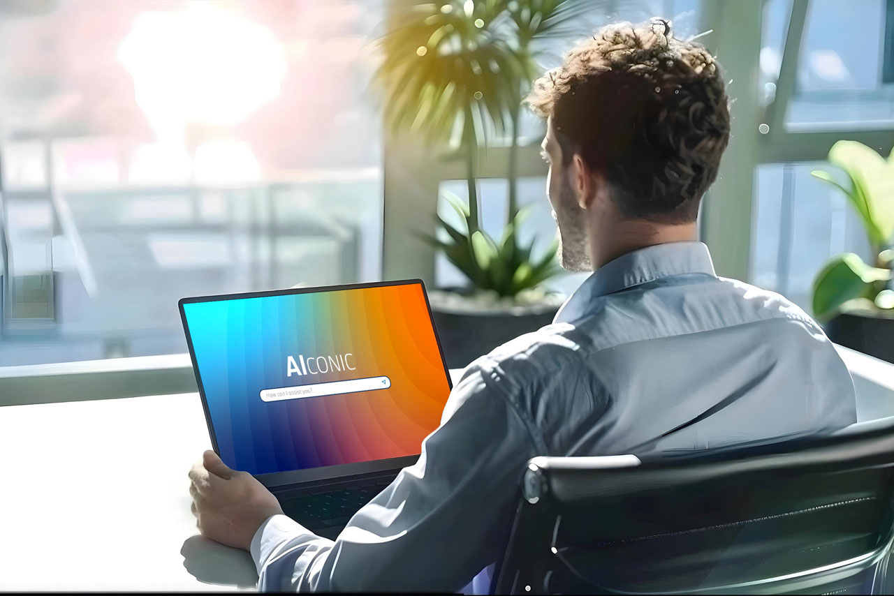 A man works on a laptop while sitting at a desk.