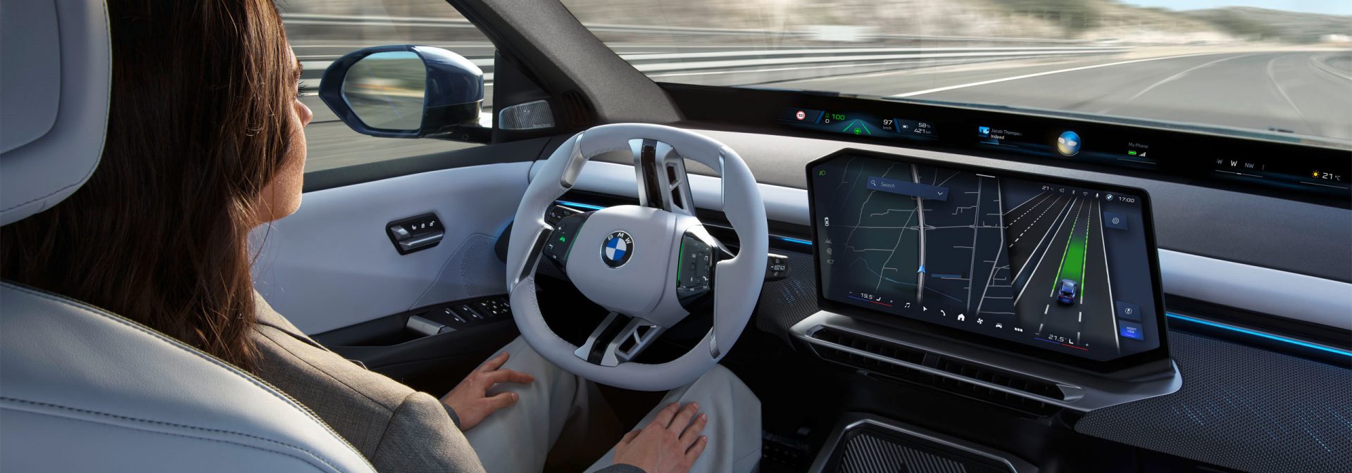 A young woman observes the traffic ahead of her on the highway, but keeps her hands on her thighs and lets the autonomous BMW drive itself.