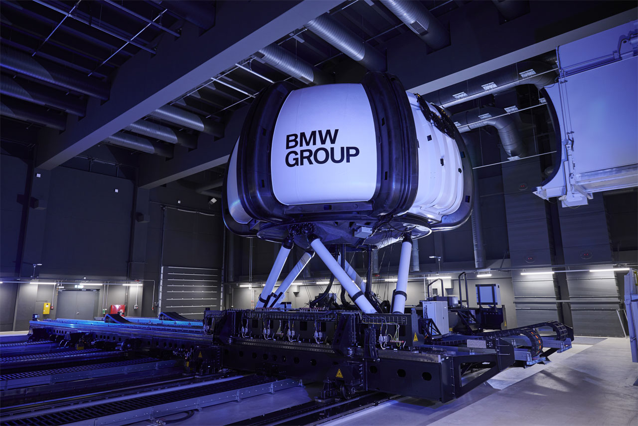 Simulator with the inscription ‘BMW GROUP’ in an industrial hall on a movable platform.