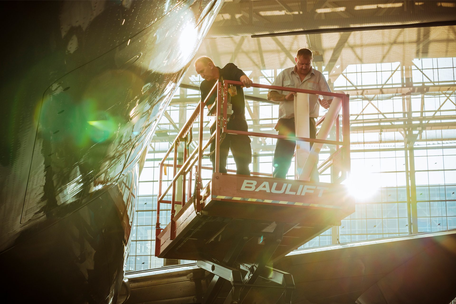 2 employees on a lifting platform on the aircraft