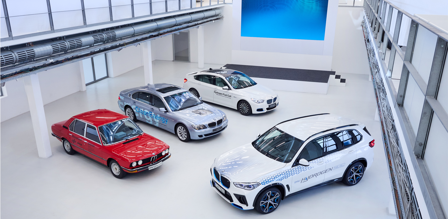Various Hydrogen Cars – from historic to modern are parked in a hall.