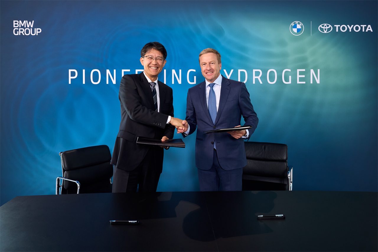 Two men, wearing suits are shaking hands.
