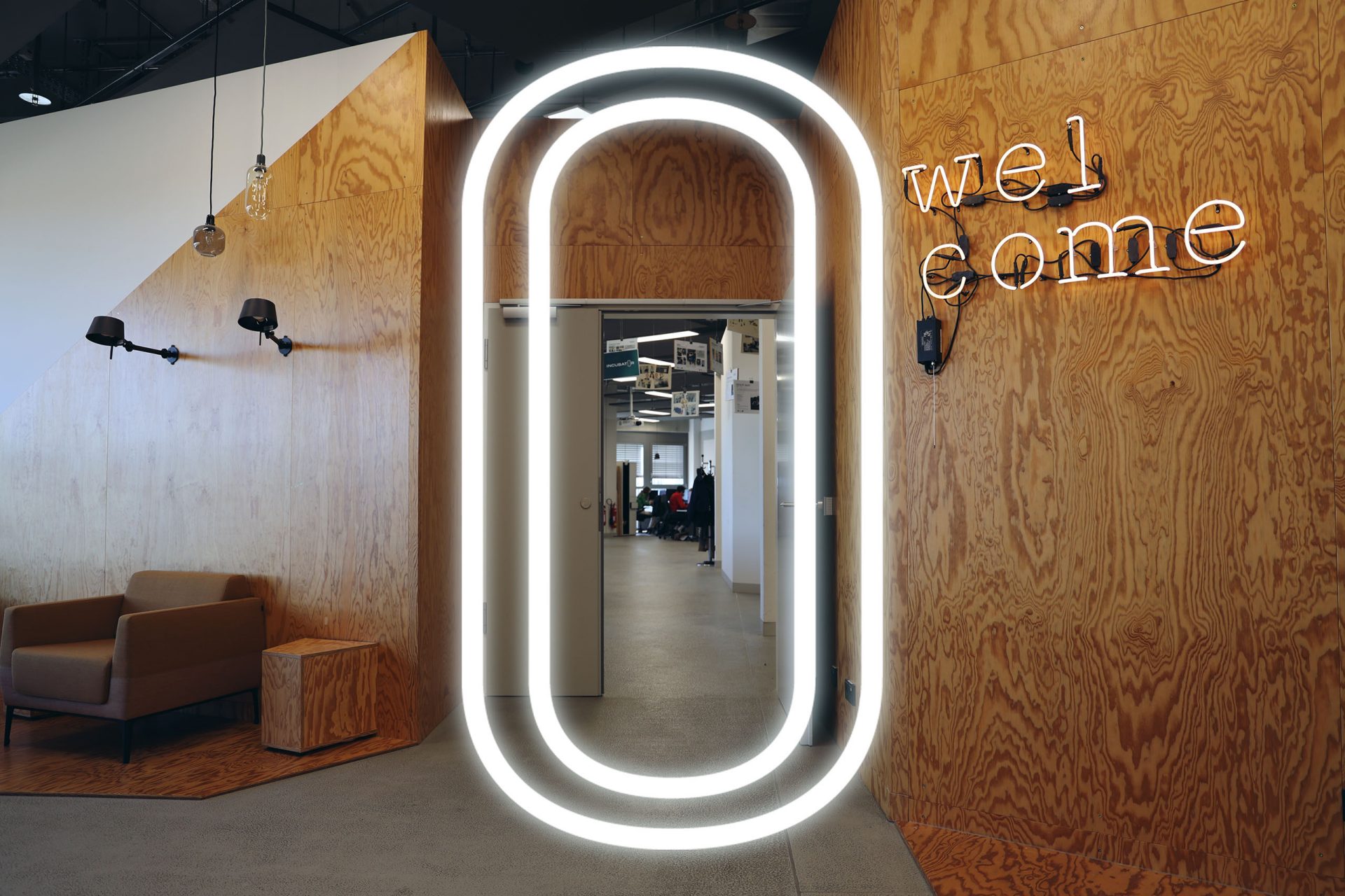 A modern office environment with wood paneling and a bright "Welcome" sign on one wall. The Open Innovation logo is integrated into the overall design.