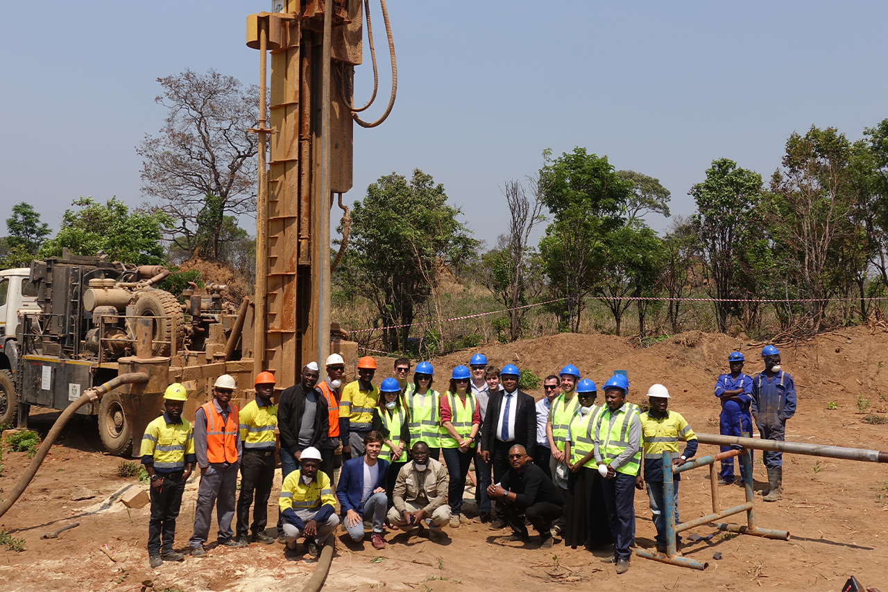 Workers of the "Cobalt for development project" stand in front of a drilling crane