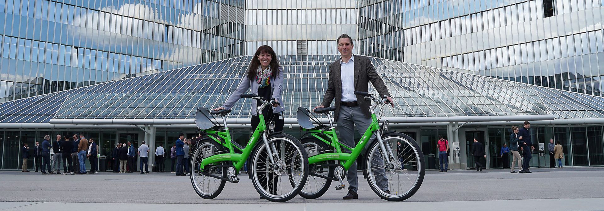 2 menschen mit Fahrrad vor Gebäude