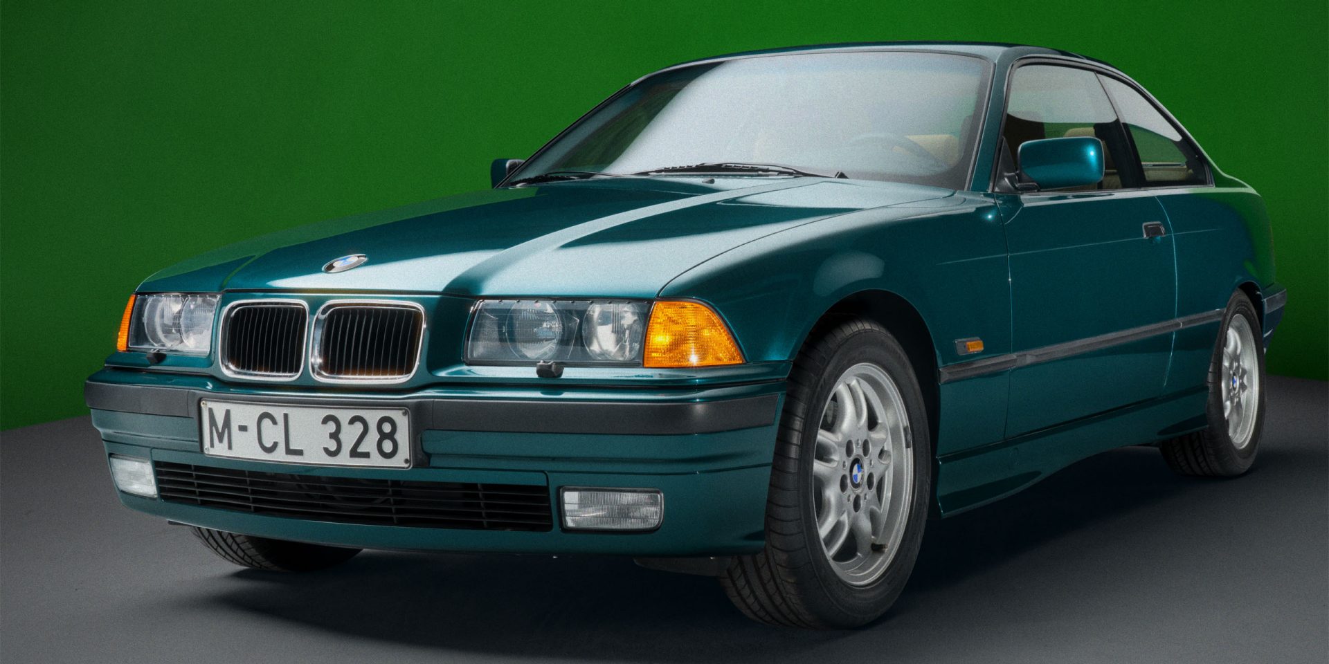A green BMW E36 Coupe seen from the front left, showing the front and side.